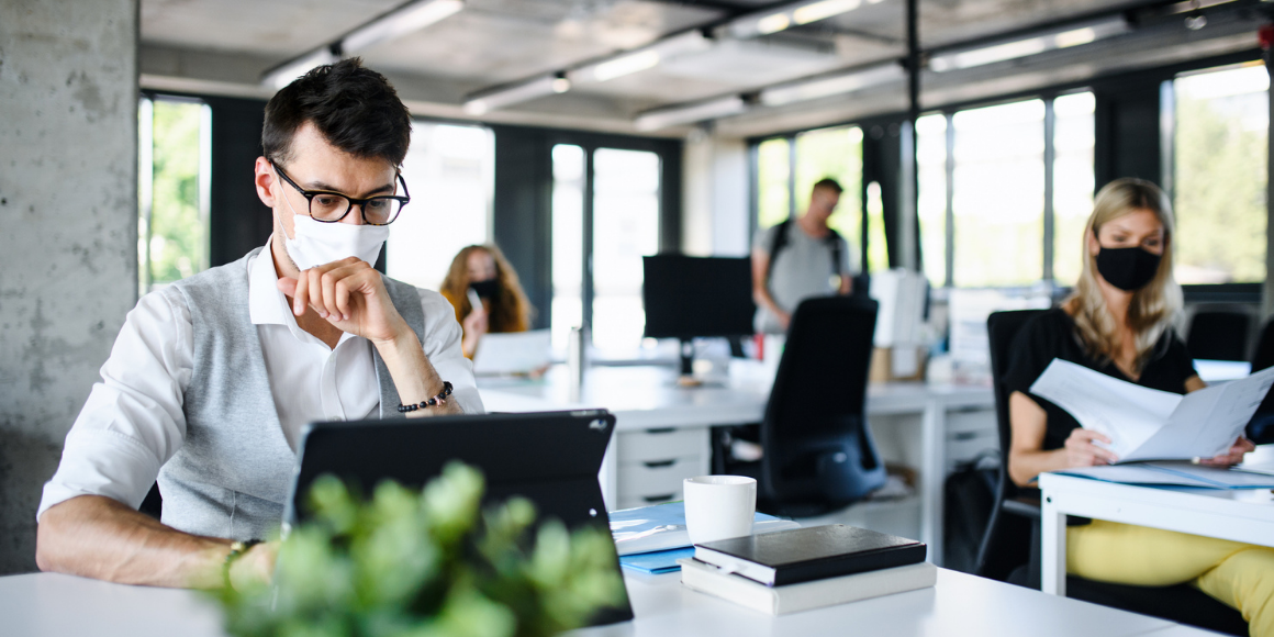 MAN WEARING MASK WORKING IN OFFICE WITH COWORKERS THANKS TO EPA REGISTERED DISINFECTANT