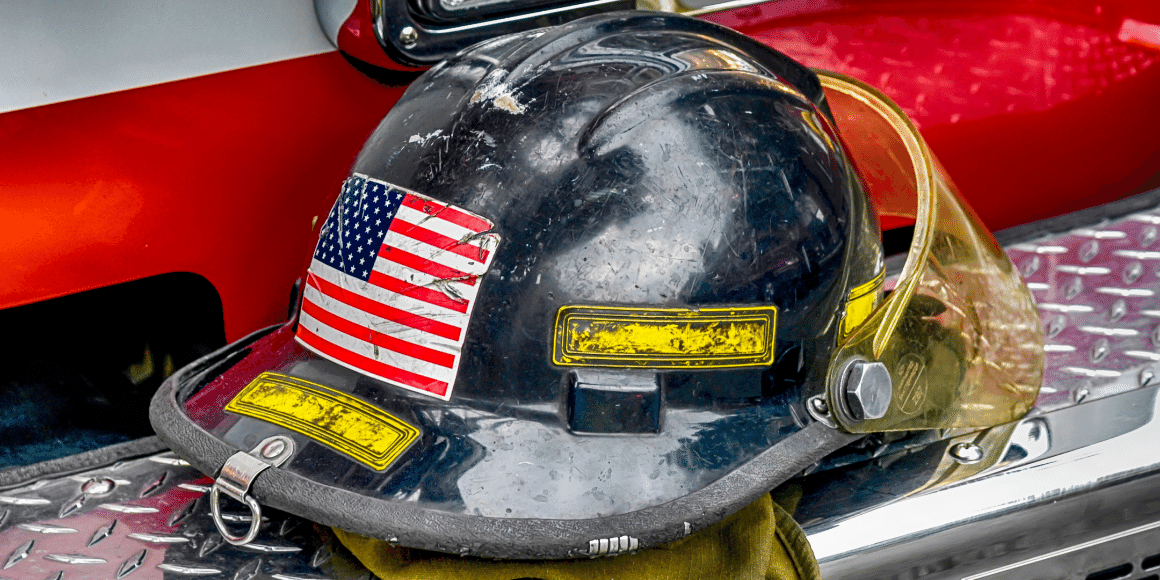 Well-used firefighter helmet resting on side of firetruck